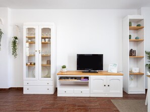 A living room with a TV, white cabinets, and shelves. - CHL La Plaza Amazing Views Tenerife (Santa Ursula)