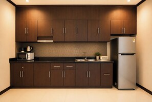 Una cucina moderna con mobili in legno scuro, un frigorifero in acciaio inossidabile, un forno a microonde e un lavello.