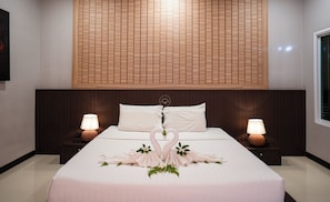 Ein Hotelzimmer mit einem großen Bett, zwei Nachttischlampen, einem Holzkopfschild und einer dekorativen Schwan-Dekoration.