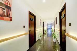 Un pasillo de hotel con puertas, plantas en macetas y un cartel que indica la habitación 104.