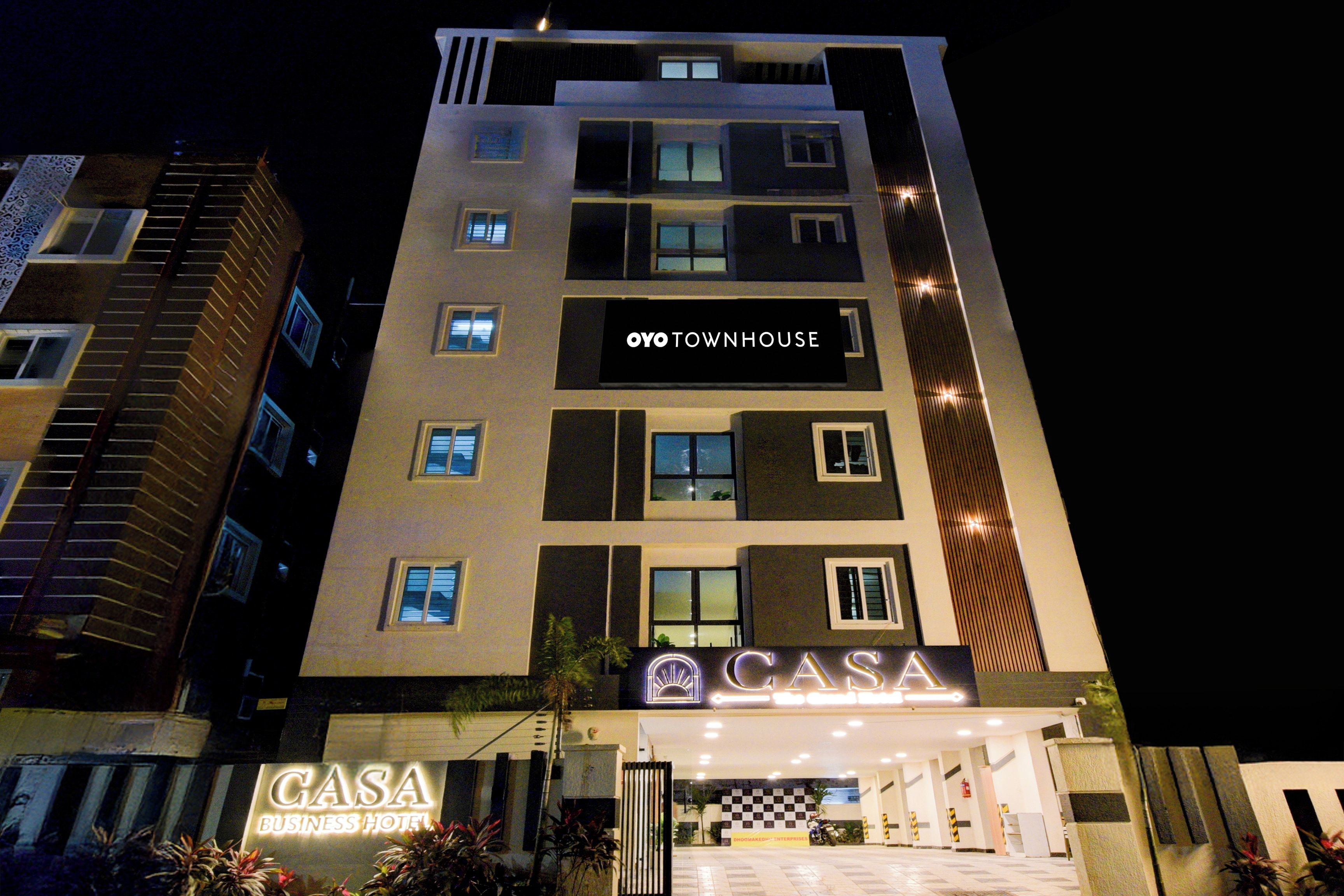 A multi-story building with a sign for 'OYO TOWNHOUSE' and 'CASA BUSINESS HOTEL' at the ground level.