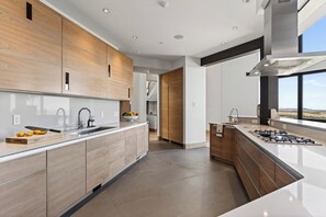 A modern kitchen with wooden cabinets, a stainless steel sink, and a gas stove. - Mountain & City Views | Hot Tub + Sauna | Trails to Mt Sanitas | Castle Black (Boulder)