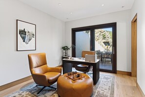 A modern living room with a leather armchair, a wooden coffee table, and a chessboard. - Mountain & City Views | Hot Tub + Sauna | Trails to Mt Sanitas | Castle Black (Boulder)