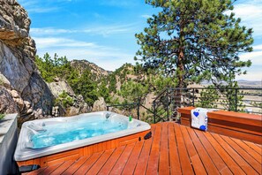 Ein Whirlpool auf einer Holzterrasse mit Blick auf Berge.
