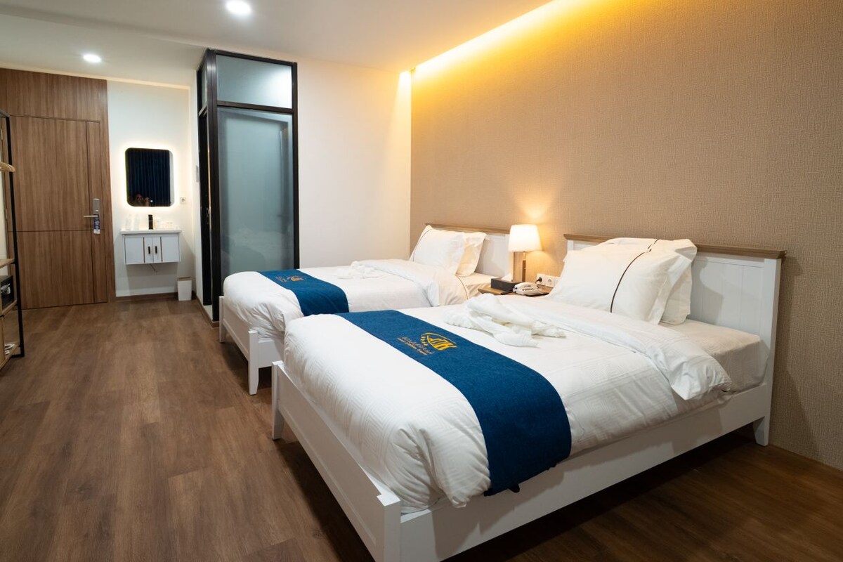 Ett hotellrum med två sängar, ett skrivbord och en spegel.