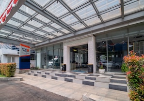 A modern building entrance with a glass facade, a blue and white sign, and a checkered floor pattern. - ODST Jakarta Transit Hotel (Tangerang)