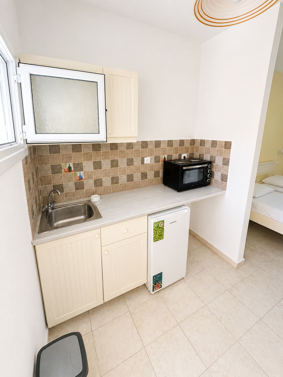 Una cocina compacta con microondas, lavamanos y un refrigerador pequeño.