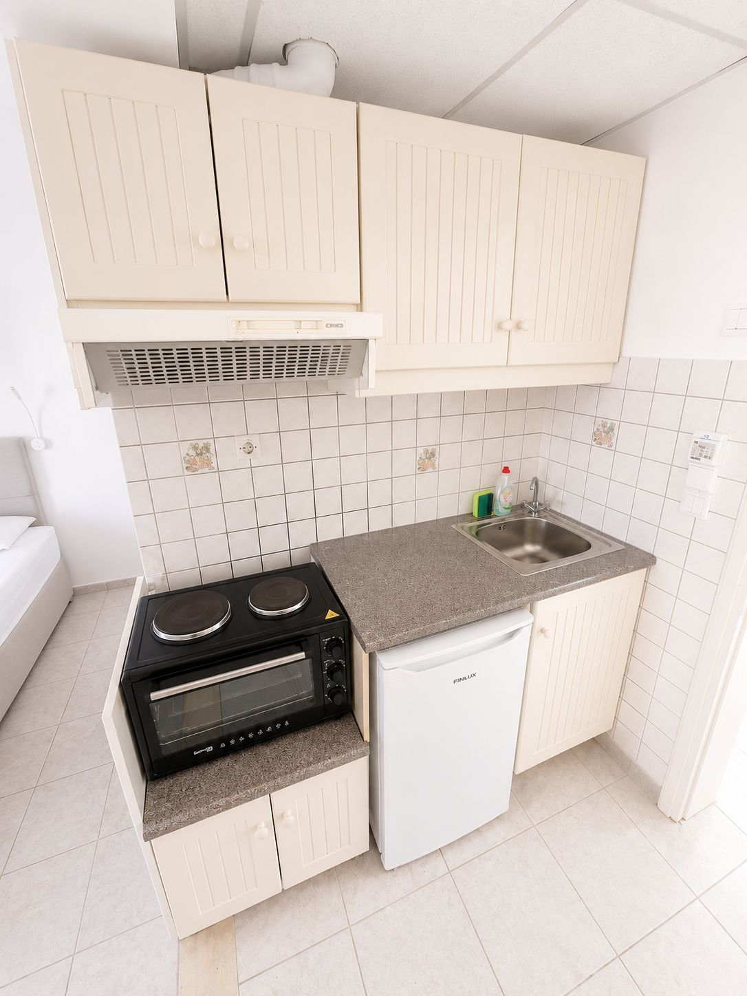 Eine kleine Küche mit Backofen, Kühlschrank und Spüle.