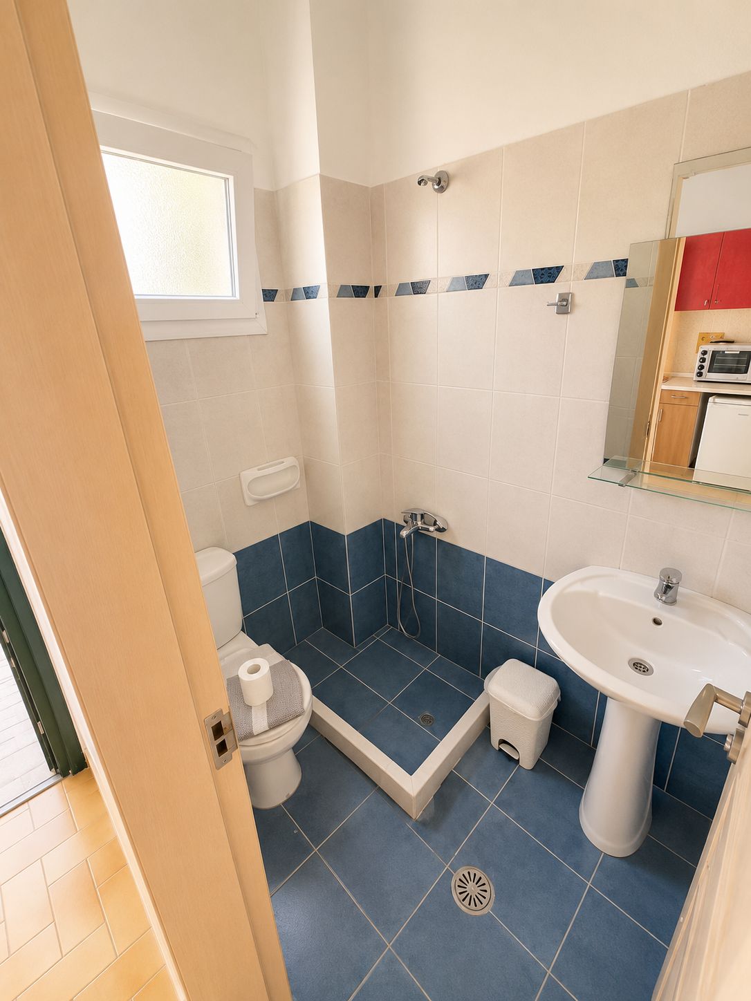 Un baño con ducha, inodoro, lavamanos y una pequeña ventana.
