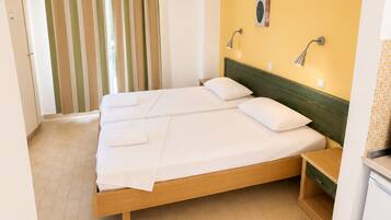 A hotel room with a double bed, a small bedside table, a wall-mounted lamp, and a television.