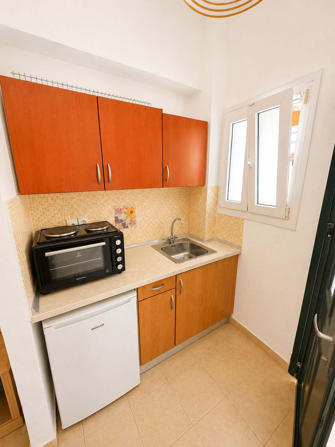 Cocina pequeña con horno tostador, pileta y muebles de madera.