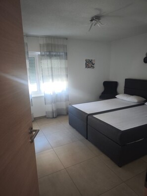 A bedroom with a bed, a ceiling fan, a window with curtains, and a wall-mounted picture. - Apartment 'Mamone' with Balcony and Wi-Fi (Gottmadingen)