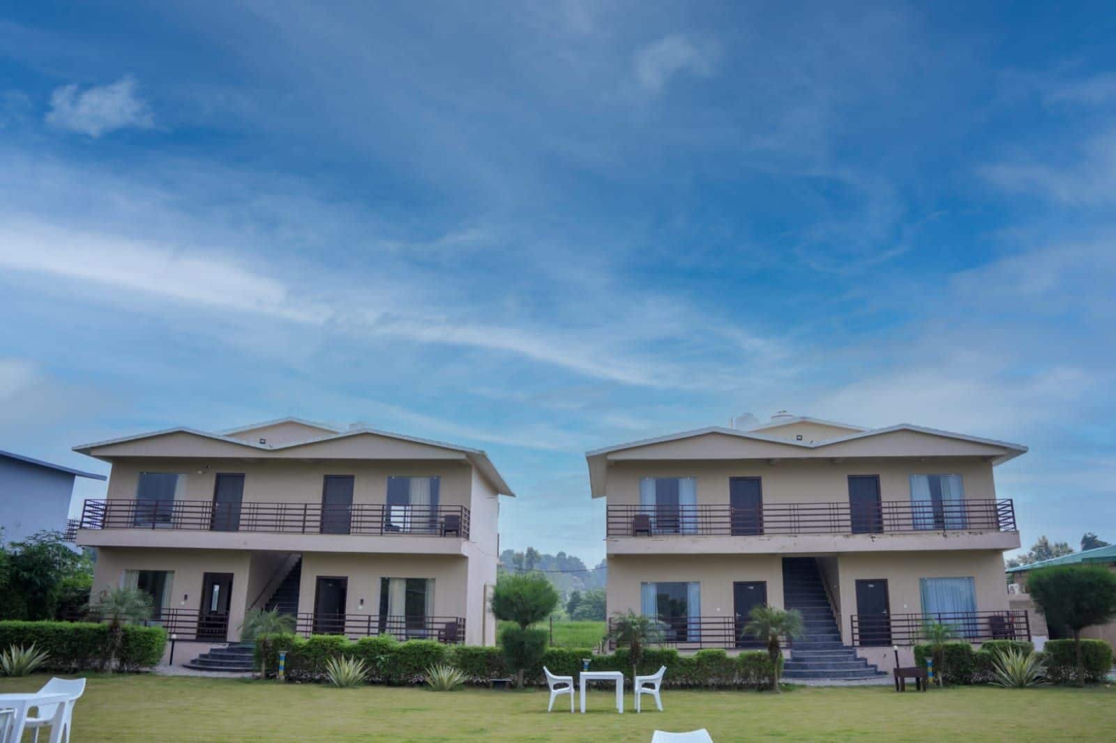 A modern two-story building with balconies, a flat roof, and a well-maintained lawn.