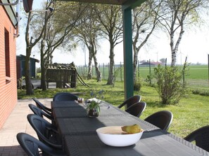 An outdoor patio with a table and chairs, a bowl of fruit, and a small plant. - Holiday Home With 5 Bedrooms (Wittmund)