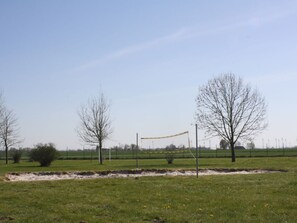 A grassy field with a volleyball net, trees, and a clear sky. - Holiday Home With 5 Bedrooms (Wittmund)