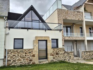 A modern building with a stone facade, a glass balcony, and a small entrance. - Premium Holiday Home, Pink Granite Coast (Perros-Guirec)