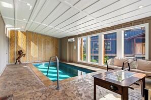En indendørs swimmingpool med en trævæg og et glastbord.