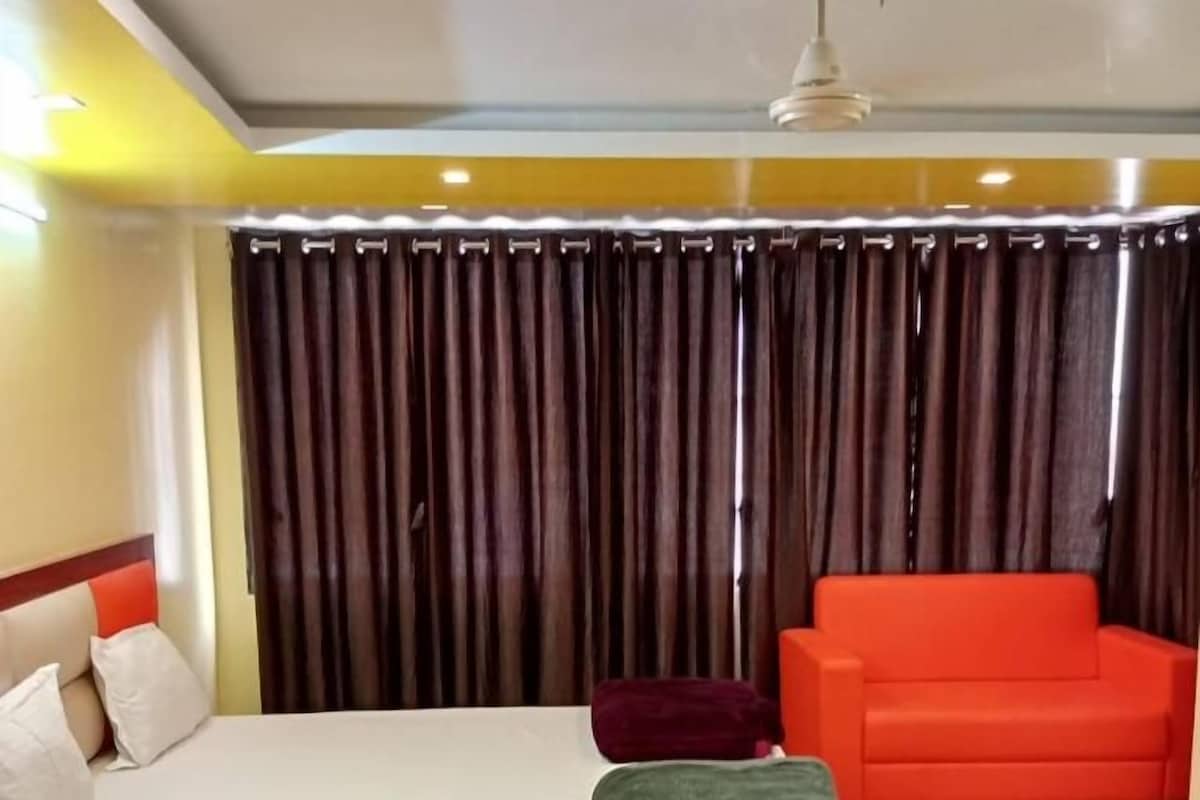 Ein Hotelzimmer mit einem Bett, einem roten Sofa und einem Vorhang im Hintergrund.