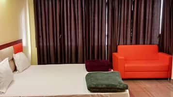 Una habitación de hotel con una cama, un sofá rojo y un telón de fondo.