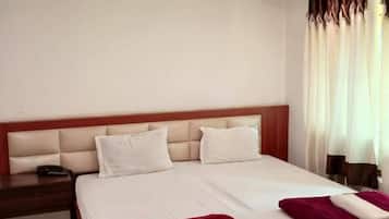 Habitación de hotel con cama doble, mesita de noche y ventilador de techo.