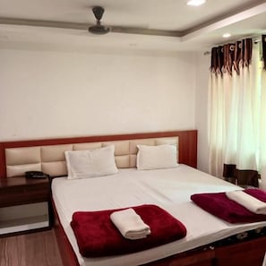 Ein Hotelzimmer mit Doppelbett, Nachttisch und Deckenventilator.