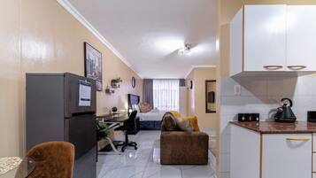 Un espacio habitable compacto con kitchenette, comedor y un dormitorio.