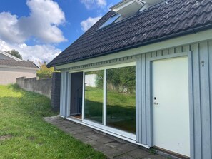 A house with a large sliding glass door, a tiled roof, and a brick wall. - 4 Star Holiday Home in Oxie (Oxie)