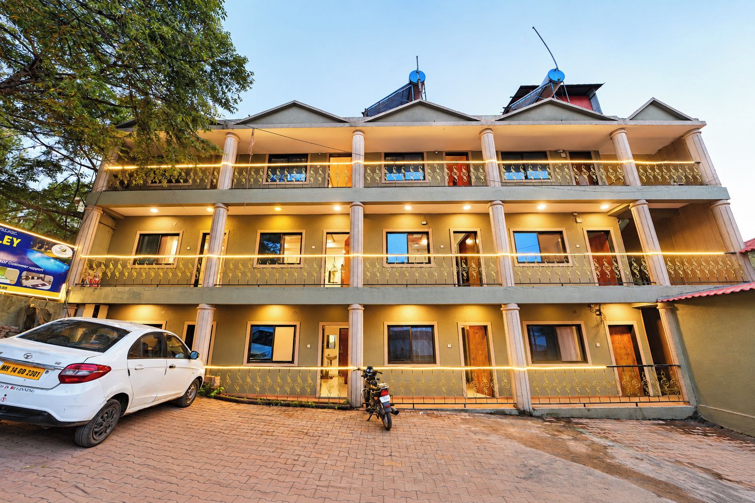 A multi-story building with balconies, a car parked in front, and a motorcycle.
