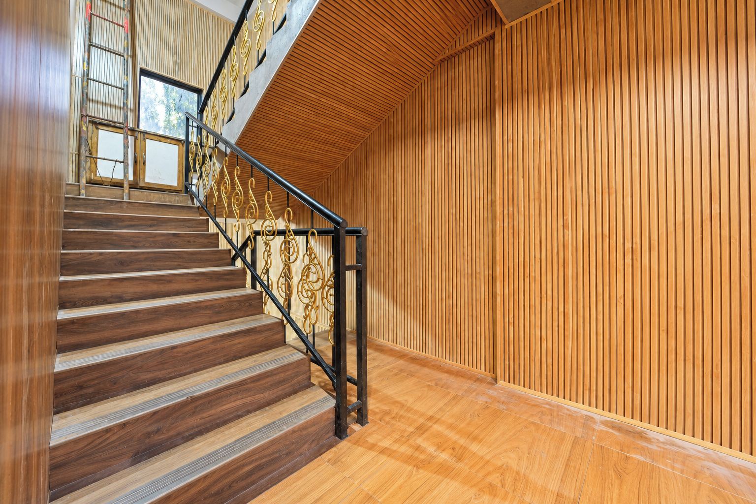 A wooden staircase with a metal railing, leading to a room with vertical wooden paneling.