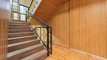 A wooden staircase with a metal railing, leading to a room with vertical wooden paneling.