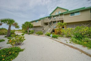 A multi-story building with a sandy driveway and a variety of tropical plants. - Closest Unit to Beach on Little Gasparilla Island (Placida)