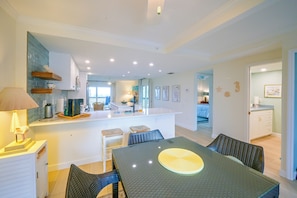 A modern kitchen with a central island, dining area with a table and chairs, and a view into the living room. - Closest Unit to Beach on Little Gasparilla Island (Placida)