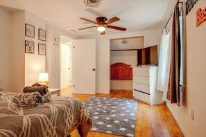 Ein Schlafzimmer mit einem Bett, einem Schreibtisch, einem Deckenventilator und einem Fernseher.