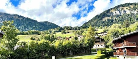 A mountain landscape with buildings, a road, and parked cars.
