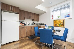 Eine kompakte Küche mit Holzausstattung, einem weißen Kühlschrank und einem Essbereich mit blauen Stühlen.