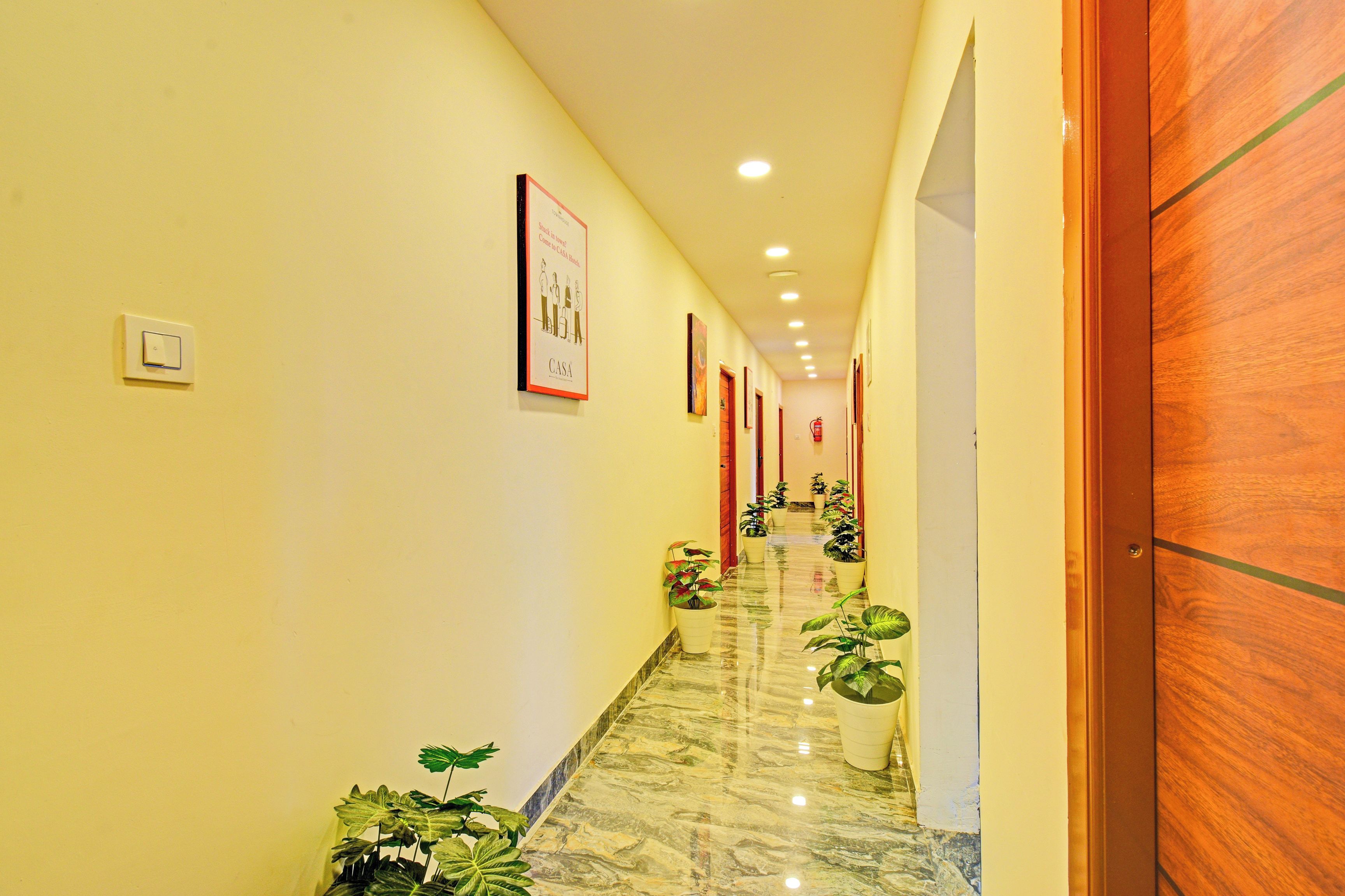 Un pasillo de hotel con piso de mármol, puertas de madera y plantas en macetas.