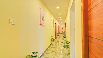Un pasillo de hotel con piso de mármol, puertas de madera y plantas en macetas.
