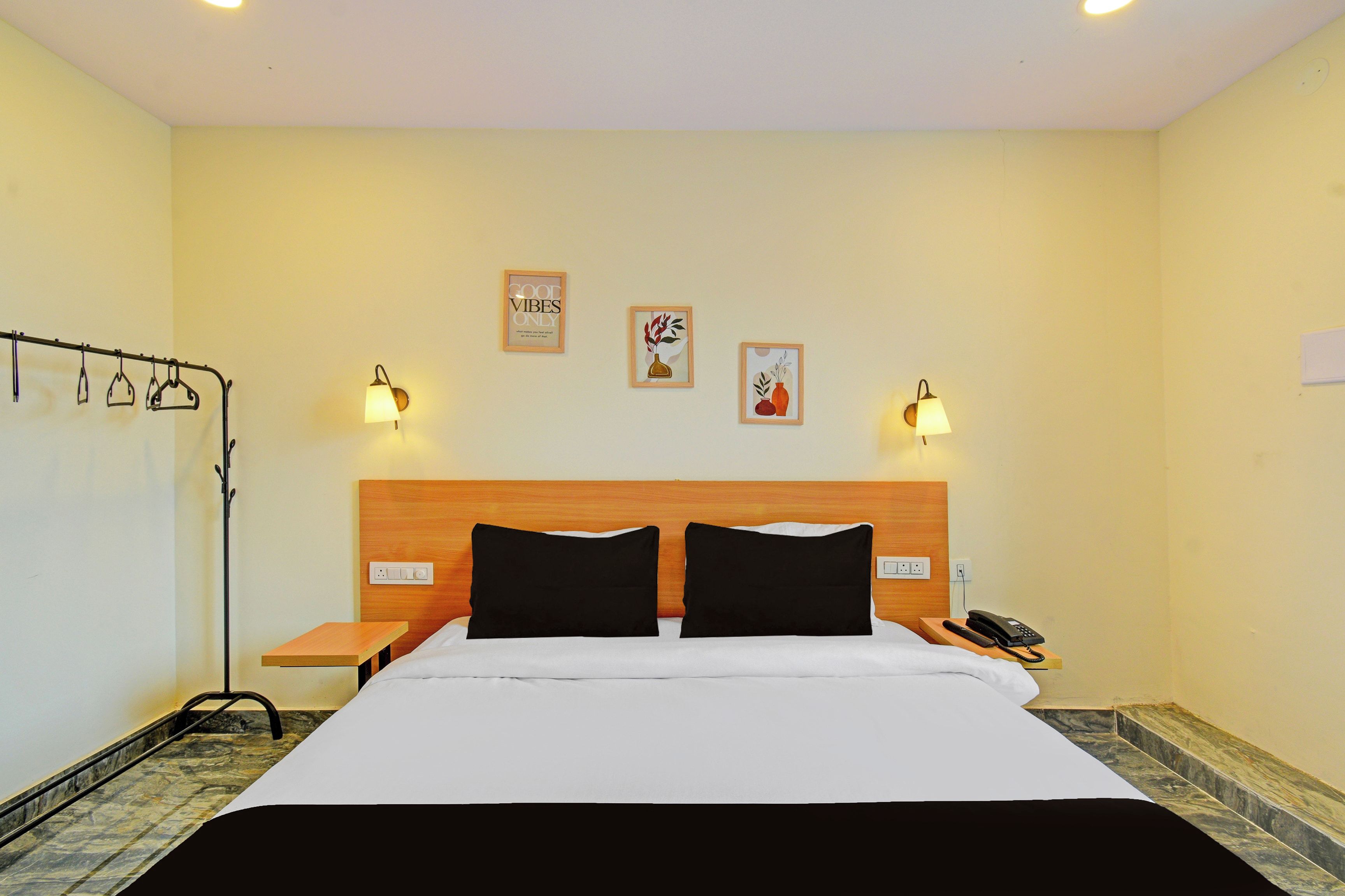 Habitación de hotel con una cama, dos mesitas de noche, un teléfono y lámparas fijadas a la pared.