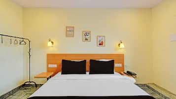 Habitación de hotel con una cama, dos mesitas de noche, un teléfono y lámparas fijadas a la pared.