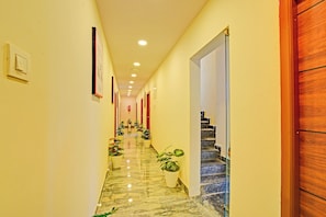 Ein Hotel-Flur mit Marmorboden, Blumentöpfen und einer Treppe zu einer weiteren Ebene.
