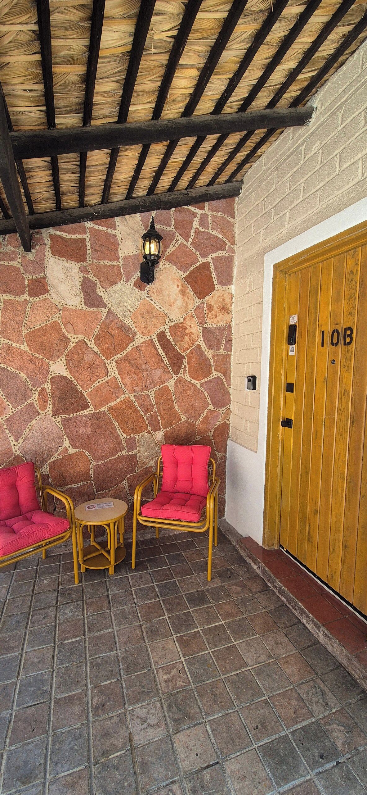 A covered outdoor seating area with stone walls and a wooden door marked '1OB'.