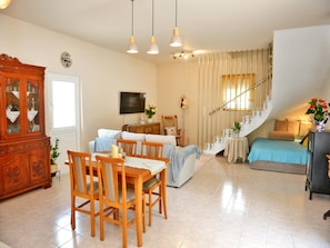 A living room with a dining area, a staircase, and a television. - Elegant Villa With Pool & Garden in Eleousis (Rhodes)