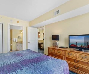Une chambre d’hôtel avec un lit, une télévision, une commode et une vue sur la mer.