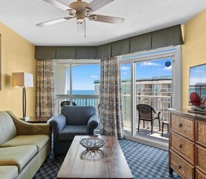 A hotel room with a balcony, a sofa, a chair, a coffee table, and a dresser. - Dunes Village Penthouse IndoorWaterParks Sleeps-12 (Myrtle Beach)
