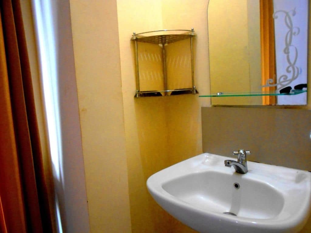A bathroom with a white sink, a glass shelf, and a towel rack.