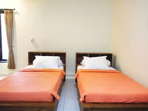A hotel room with two single beds, each with a wooden headboard and a white pillow. The beds have orange bedding. - Puri Asri Bungalow Ubud (Ubud)