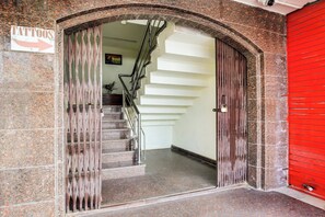 A staircase leading to an upper floor, with a sign indicating a tattoo parlor on the left.
