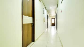 Um corredor comprido e estreito, com portas de um lado e chão de azulejos.