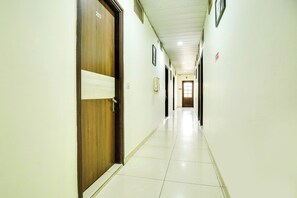 A long, narrow hallway with doors on one side and a tiled floor.