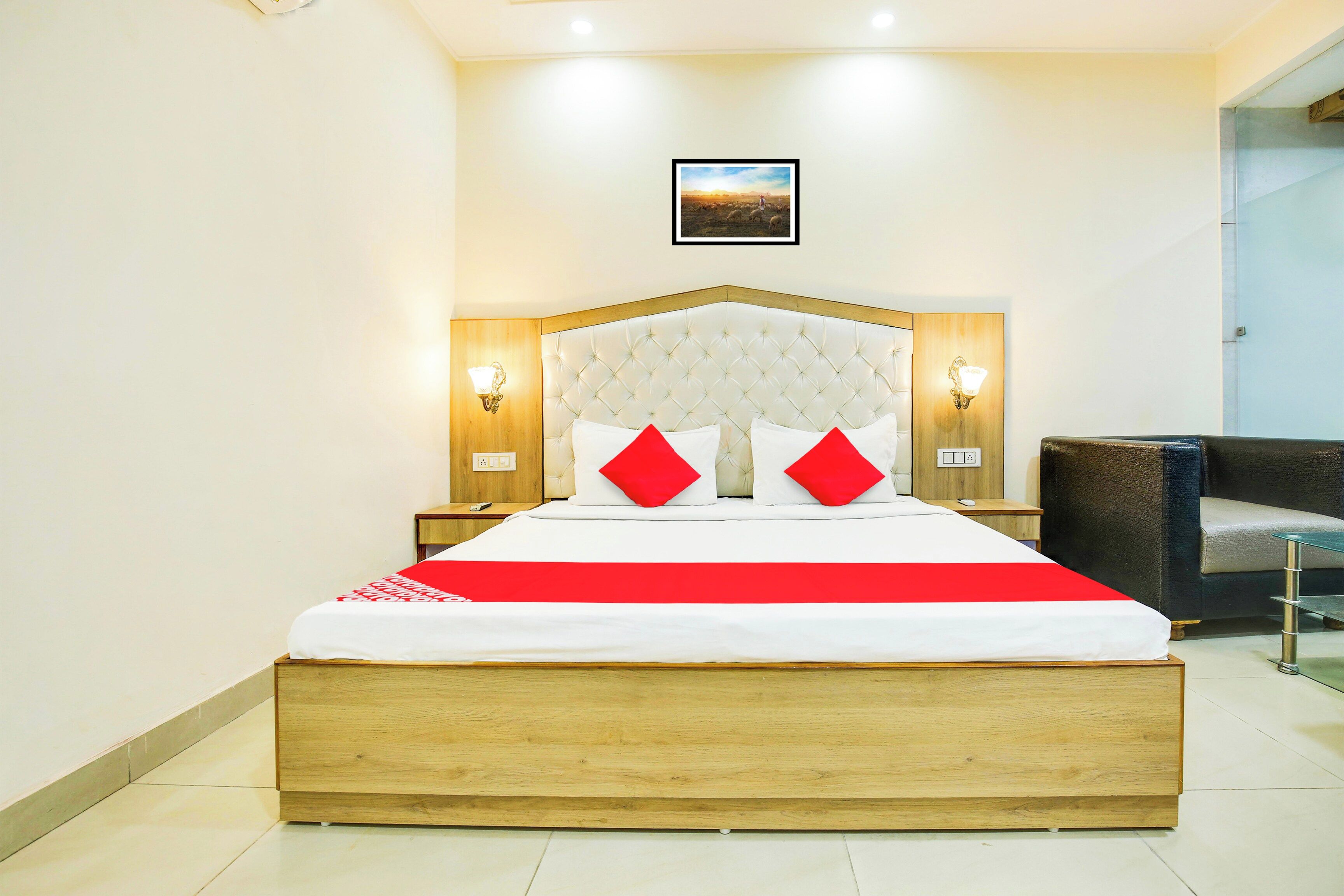 A hotel room with a large bed, two bedside lamps, a framed picture on the wall, and a chair in the corner.
